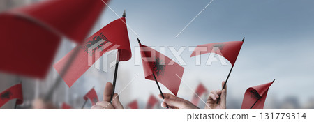 Albania flags in their hands on a blurred urban background Albania flags in their hands on a blurred urban background 131779314