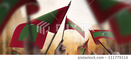 Maldives flags in their hands on a blurred urban background Maldives flags in their hands on a blurred urban background 131779318