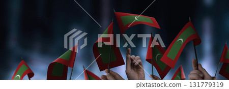Maldives flags in their hands on a blurred urban background 131779319