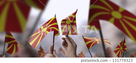 Macedonia flags in their hands on a blurred urban background Macedonia flags in their hands on a blurred urban background 131779323