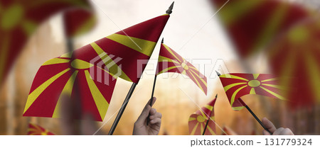 Macedonia flags in their hands on a blurred urban background Macedonia flags in their hands on a blurred urban background 131779324