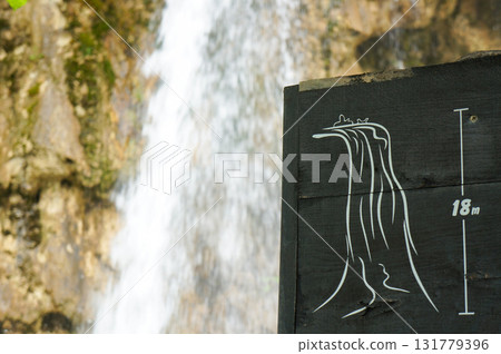 A sign indicating the height of the waterfall and the waterfall itself 131779396