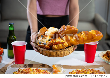 Women's hands holding breakfast, croissants, bakery, pizza on the table, preparing a party. 131779547