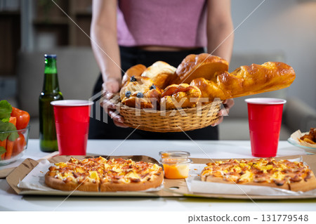 Women's hands holding breakfast, croissants, bakery, pizza on the table, preparing a party. 131779548