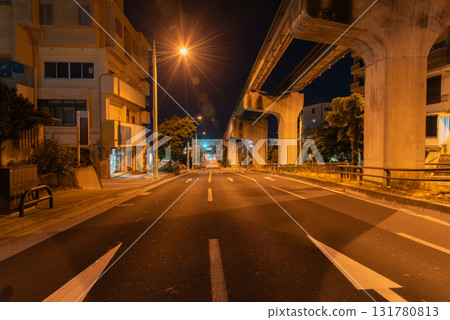 Monorail rails and roads late at night under bright orange street lights Monorail rails and roads late at night under bright orange street lights 131780813