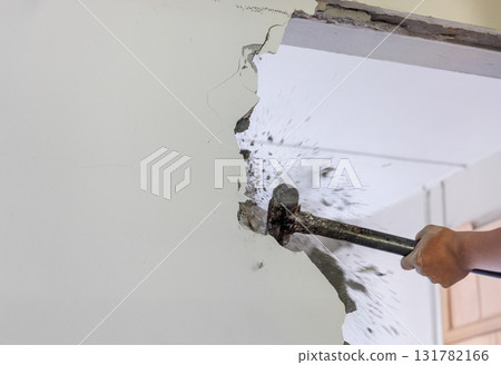 Worker breaking wall with sledgehammer in renovation house. Worker breaking wall with sledgehammer in renovation house. 131782166