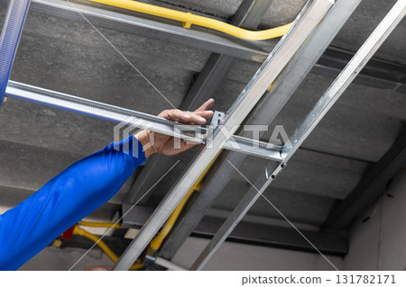 Worker is installing metal profiles for gypsum board ceiling in renovate house. Worker is installing metal profiles for gypsum board ceiling in renovate house. 131782171