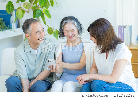 Senior couple and child looking at smartphone in the living room 131782283