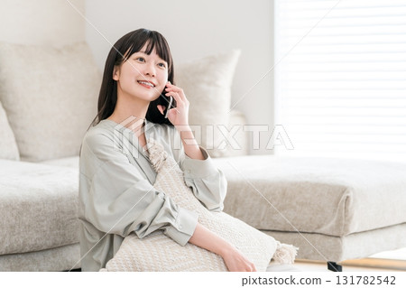 Japanese woman calling on smartphone (home, living room, smiling) 131782542