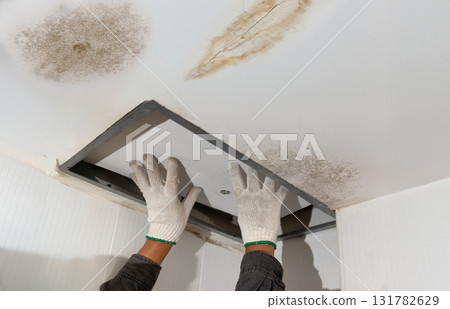 Worker fix leaking pipe in ceiling ,close-up of a stain on the ceiling. 131782629
