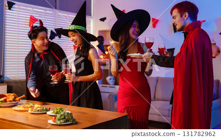 Dinner and group of people celebrating together at Halloween party. 131782962