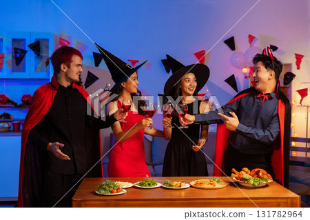 Dinner and group of people celebrating together at Halloween party. 131782964