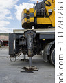 A large yellow and black Hidromek HMK 310 crane mounted on a flatbed truck is parked in a construction site. 131783263