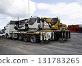 A large y white and yellow Hidromek HMK 310 crane mounted on a flatbed truck is parked in a construction site. 131783265
