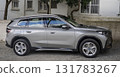 A modern silver BMW with sleek lines, a black roof, and distinctive LED taillights, is parked in a driveway. 131783267