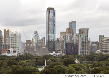 a modern Bangkok city skyline in the evening, featuring illuminated skyscrapers set against a cloudy sky. 131783760