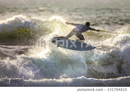 A surfer rode the wave in a jump, splashing A surfer rode the wave in a jump, splashing 131784810
