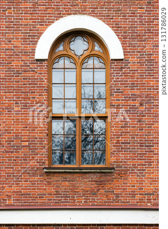 Red brick exterior featuring a wooden-framed window with Gothic details 131786029