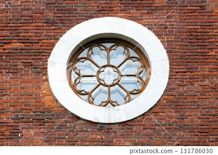 A decorative circular window with intricate frame sits in a white stone circle A decorative circular window with intricate frame sits in a white stone circle 131786030