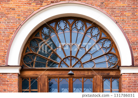 A grand arched window with decorative wooden frame. Front view, background photo A grand arched window with decorative wooden frame. Front view, background photo 131786031