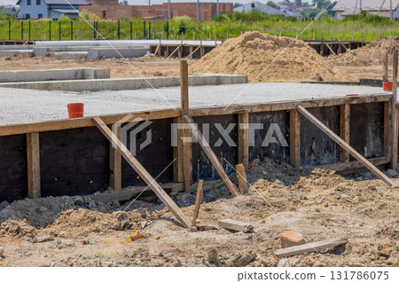 Cement is being poured to create the foundation for a house in a developing area, showcasing the groundwork for future construction Cement is being poured to create the foundation for a house in a developing area, showcasing the groundwork for future construction 131786075