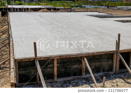 Workers prepare a cement slab for the foundation of a house in a residential construction site during a bright day Workers prepare a cement slab for the foundation of a house in a residential construction site during a bright day 131786077