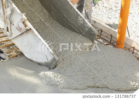 Pouring fresh ready-mixed concrete from wheelbarrow on floor during for construction of a house Pouring fresh ready-mixed concrete from wheelbarrow on floor during for construction of a house 131786737