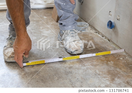 Craftman measuring floor before tiling, hands closeup. Construction or  Home Remodeling 131786741