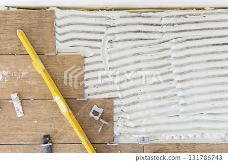 Process of tiling a room, tiles and floor prepared with adhesive, top view. Construction of a house 131786743