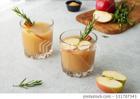 Hot apple cider with cinnamon, anise, and rosemary in glasses on a light background Hot apple cider with cinnamon, anise, and rosemary in glasses on a light background 131787343