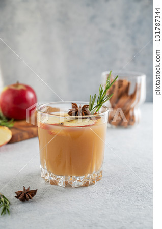 Hot apple cider with cinnamon, anise, and rosemary in glass on a light background Hot apple cider with cinnamon, anise, and rosemary in glass on a light background 131787344