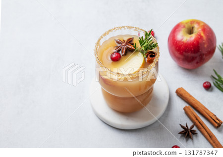 Apple cider with cinnamon, anise, brown sugar and rosemary in a glass on a light background 131787347