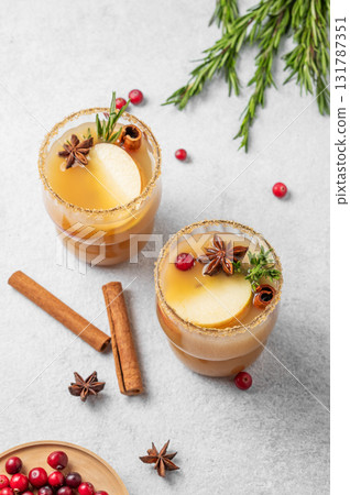 Two glasses of hot apple cider with cinnamon, anise, brown sugar and rosemary on a light background 131787351