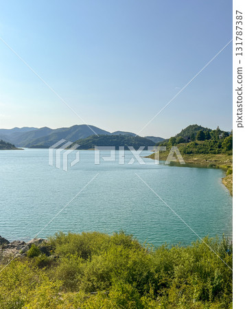 Panoramic and picturesque view of a lake with calm water against the backdrop of forested hills. Panoramic and picturesque view of a lake with calm water against the backdrop of forested hills. 131787387