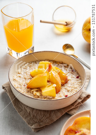 Oatmeal with peaches and nuts  in a bowl on a light background with honey 131787531