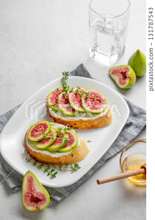 Sweet toasts with fresh figs, cheese, thyme, and honey on a light background. Sweet toasts with fresh figs, cheese, thyme, and honey on a light background. 131787543