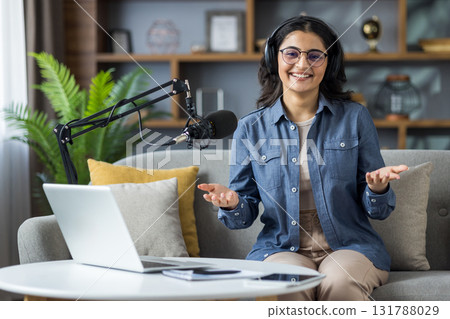 A smiling woman in glasses and headphones ready to start her podcast recording session, talking. A smiling woman in glasses and headphones ready to start her podcast recording session, talking. 131788029