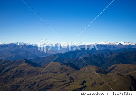 Panoramic view of Caucasus Mountains with snow-capped peaks , hills under blue sky. Natural landscape symbolizing freedom, purity, beauty of wild nature. For travel, adventure, eco-tourism concepts. 131788353