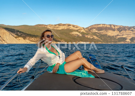 Woman, yacht, vacation. Relaxing on a luxury boat at sea with mountains in background 131788607