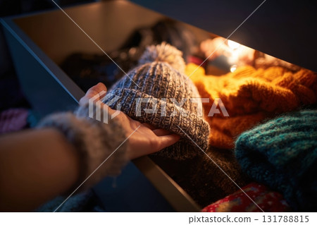 Hand Reaching for Cozy Beanie in Drawer of Winter Accessories 131788815
