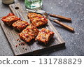Grilled baked pork ribs with spices on wooden cutting board on dark background. American food concept. 131788829