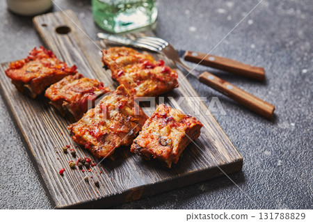 Grilled baked pork ribs with spices on wooden cutting board on dark background. American food concept. 131788829
