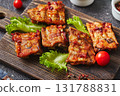 Grilled baked pork ribs with spices and vegetables on wooden cutting board on dark background. American food concept. 131788831