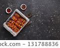 Roasted pork ribs in foil in metal baking dish. American food concept. Top view, copy space 131788836