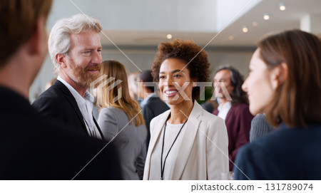 Diverse group of smiling business people talking at professional networking meeting. Corporate colleagues enjoying conversation during break at large conference 131789074