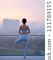 Calm woman practicing yoga pose on balcony during beautiful sunrise. healthy lifestyle and wellness concept with peaceful cityscape view in background 131789155