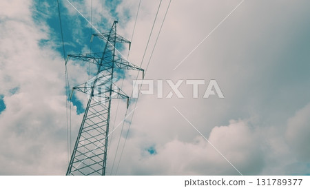 Tall Power Lines Rising High Against a Dramatic, Cloudy Sky, Creating a Striking Landscape 131789377