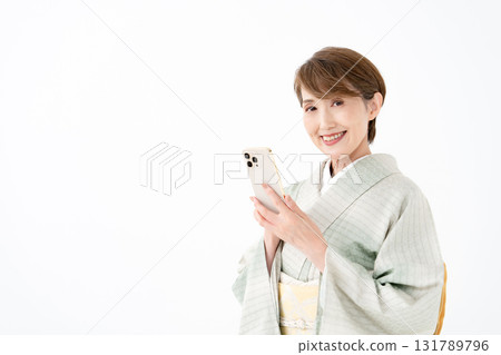 A woman in a kimono holding a smartphone A woman in a kimono holding a smartphone 131789796