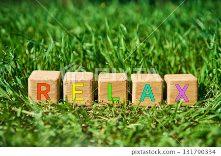Wooden cube blocks with multicolor RELAX text on fresh green grass Wooden cube blocks with multicolor RELAX text on fresh green grass 131790334