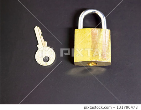 A bronze-colored lock and a key next to it on a black background, a security concept, as well as a concept of cybersecurity and data protection, with empty space for text A bronze-colored lock and a key next to it on a black background, a security concept, as well as a concept of cybersecurity and data protection, with empty space for text 131790478